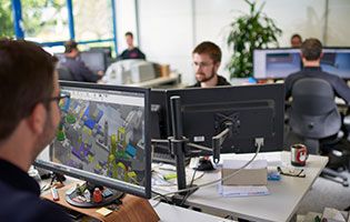 Mitarbeiter von QSQ sitzen in der Entwicklungsabteilung vor Bildschirmen.